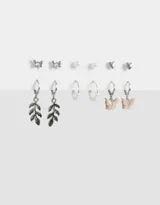 Set de seis pares de aros plateados con diferentes diseños: aros tipo botón con forma de mariposa y corazón, aros con forma de perla y aros colgantes con dijes de hojas, flores y mariposas rosas.