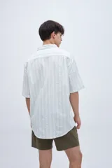 Camisa de manga corta a rayas verticales blancas y verdes, con cuello solapa clásico, bolsillo en el pecho y botones personalizados.