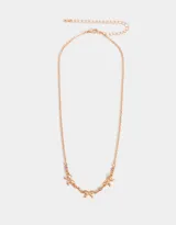 Collar corto bañado en oro rosa con cadena de eslabones y tres dijes de moño con strass rosado.