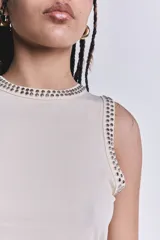 Musculosa color crudo de punto canalé, con cuello redondo y sisas con apliques de tachas plateadas.