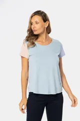 Remera de manga corta con cuello redondo y diseño a bloques de color en tonos celeste, gris y rosa.