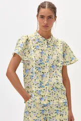 Camisa amarilla de lino con estampado floral en tonos azules, cuello mao y mangas cortas con volados. Cierre frontal con botones. Marca Francesca.