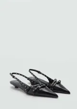 Zapato negro de punta fina con cierre de hebilla, detalles troquelados y tacón kitten.