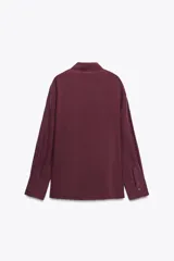 Camisa marrón de seda 100% con cuello solapa, manga larga con puños abotonados, bajo asimétrico redondeado y cierre frontal con botones.