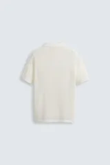 Polo blanco de punto tejido con estructura calada, corte regular fit, cuello solapa con abertura frontal y manga corta.