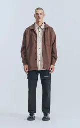 Chaqueta marrón de paño con cuello clásico, cierre frontal con botones, dos bolsillos de parche en el pecho y corte holgado.