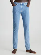 Jeans celeste de corte slim fit, tiro medio y pierna cónica. Diseño clásico de cinco bolsillos, con cierre de botón y cremallera.