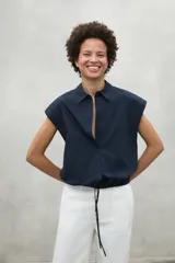 Camisa azul marino con cierre frontal de botones y dobladillo ajustable con cordones de tela.