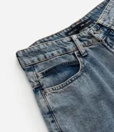 Bermuda baggy de jeans color gris oscuro con pespuntes contrastantes, cierre de botón y cremallera, y bolsillos.