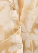Camisa de manga larga color beige con estampado floral, cuello camisero y cierre frontal con botones.