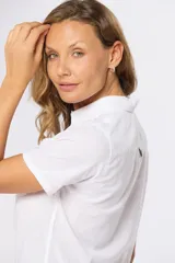 Camisa color beige de lino y algodón, de manga corta, con cuello clásico, medio abotonado y dos bolsillos en el pecho.