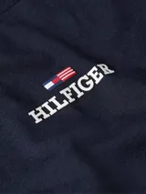 Remera azul marino de algodón con cuello redondo y corte regular. Presenta el logo de Tommy Hilfiger bordado en el pecho y la bandera de la marca bordada en la manga.