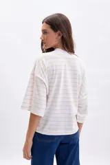 Remera de manga tres cuartos, corte holgado, color blanco con finas rayas horizontales en tono amarillo pálido. Presenta cuello alto tipo mock neck.