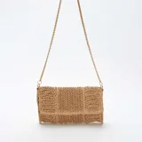 Bolso de mano color beige confeccionado en rafia trenzada, con diseño rectangular y bandolera de cadena dorada.