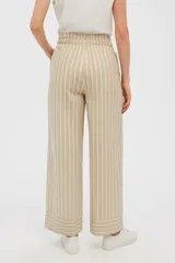 Pantalón ancho color beige con rayas verticales blancas, cintura alta con cordón ajustable y bolsillos laterales.