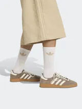 Bermuda color beige de corte ancho con tres líneas verticales a los costados y logo de la marca bordado en la pierna izquierda.