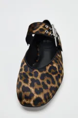 Zapato plano tipo bailarina con estampado animal, tira sobre el empeine con hebilla metálica y punta redondeada.