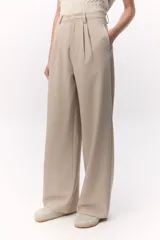 Pantalón sastrero de tiro alto color beige, con pierna ancha y pinzas frontales.
