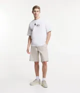 Bermuda de hombre, modelo loose con corte de sastrería, confeccionada en sarga de algodón y elastano. Color beige claro, con cierre de botón y cremallera, bolsillos y bajo ancho.