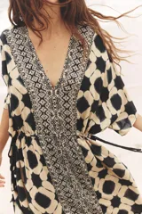 Vestido amplio estilo caftán con estampado geométrico en tonos beige y azul, escote en pico con lentejuelas y manga ancha por debajo del codo. Cintura ajustable con cordones con borlas.