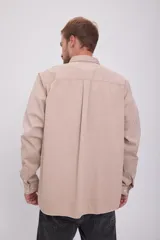 Camisa de manga larga color beige, con cuello clásico, cierre con botones y bolsillo en el pecho. Corte recto.