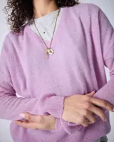 Sweater de cashmere color lila con cuello en V, corte oversize, mangas largas, hombros caídos y terminaciones acanaladas.