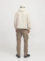 Campera shell ligera color beige, de manga larga con capucha y fit cómodo. Confeccionada en tejido plano fino de nylon, con cierre frontal de cremallera, bolsillos delanteros funcionales y puños de canalé.