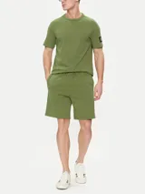 Remera verde oliva de algodón, corte clásico, cuello redondo y manga corta. Presenta una insignia con el monograma de Calvin Klein en la manga.