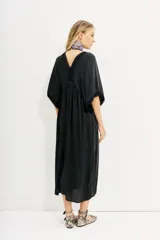Vestido midi negro de calce amplio y mangas al codo. Tiene apliques de gasa en escote y mangas, y recortes con frunce en la cintura.