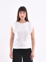 Remera blanca de mangas cortas con volados en los hombros.