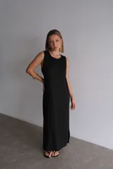 Vestido largo azul marino de tejido acanalado, con escote redondo y mangas cortas tipo hombrera. Presenta una abertura lateral en la falda.