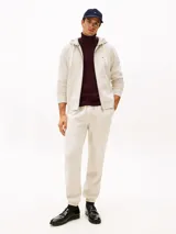 Buzo con capucha y cierre de cremallera, confeccionado en felpa de mezcla de algodón color crema. Tiene dos bolsillos delanteros tipo canguro, puños y bajo de punto canalé.