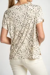 Remera color crema con estampado de manchas marrones, de corte oversize, con cuello en V y mangas cortas.