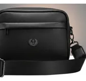 Bandolera negra de cuero sintético con correa ancha ajustable y desmontable. Cuenta con cierre superior, bolsillo frontal con tiracierre customizado, forro interno y cuatro bolsillos en total (dos exteriores y dos interiores).