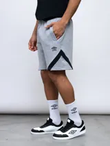 Bermuda deportiva gris de algodón, poliéster y elastano, con detalles en negro en los laterales y logo Umbro en la pierna izquierda.