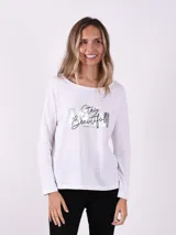 Remera blanca de manga larga con cuello redondo y estampado plateado con la frase 'Stay Beautiful'.