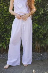 Pantalón blanco de algodón con textura de pequeños rombos, corte amplio y cintura elastizada con cordón ajustable.