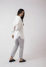 Camisa blanca de lino, de corte holgado, con cuello clásico, cierre frontal con botones, bolsillo en el pecho y mangas largas con puños abotonados.