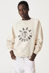 Sudadera lila de algodón con cuello redondo y mangas largas. Estampado en el frente con el logo "Zara A Coruña" y el texto "Est. 1975".
