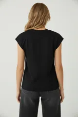 Remera negra de algodón, de corte holgado, con cuello redondo a la base y mangas cortas tipo 'cap sleeve' o al hombro.