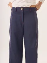 Pantalón de pierna ancha color azul marino con pespuntes a contratono (rojo/bordó) y una tira contrastante en el lateral.