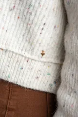 Sweater de tejido de punto color blanco roto con efecto tweed o confeti, caracterizado por pequeñas motas de colores. Presenta cuello redondo y un calce holgado (oversize).