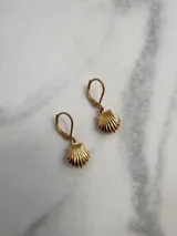 Par de aros colgantes dorados con forma de concha marina.