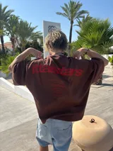 Remera color crema de corte holgado con estampado en rojo en la espalda con el texto "Ittaistars European Tour by Ittai Stars Company".