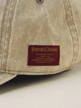 Gorra de gabardina color gris oscuro con visera curva y etiqueta con logo de la marca en el lateral.