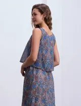 Vestido largo sin mangas de gasa estampada en tonos azules y marrones. Presenta escote redondo y corte en la cintura con punto smock.