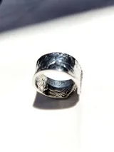 Anillo de acero inoxidable plateado con diseño grabado inspirado en monedas, apertura ajustable.