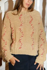 Sweater tejido a mano con lana merino color negro y bordado con lana color crudo. Es corto, a la cintura y de cuello alto.