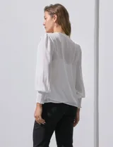 Blusa blanca de gasa marca Tahari, con escote en V, apliques de botones y detalle de punto smock en hombros y puños. Incluye musculosa a tono.
