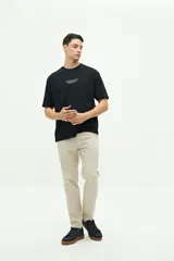 Remera negra de manga corta con estampado en la espalda de un globo terráqueo con el texto "Wild World Tour" y nombres de ciudades.